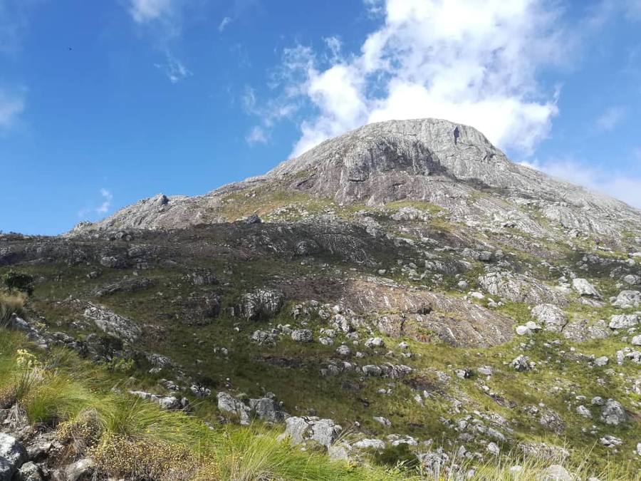 The rounded granite dome of Chambe peak above green and rocky slopes.