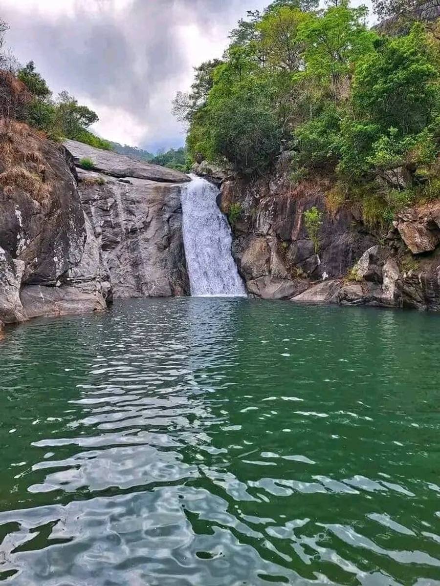 Dziwe la Nkhalamba — a waterfall dropping down a granite slab into a deep green pool ringed by forest.