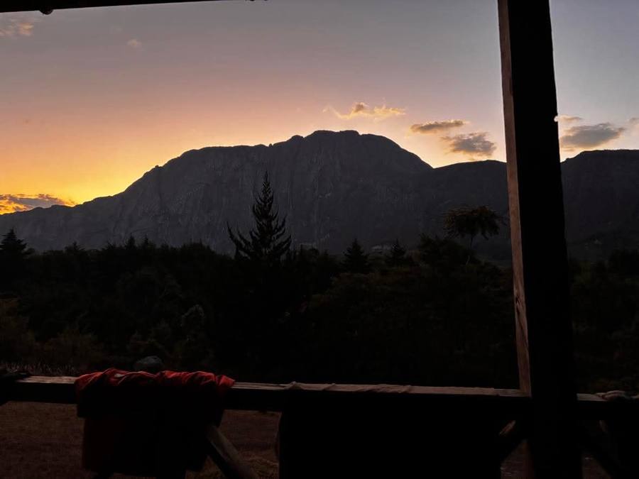 The silhouette of the Mulanje massif at dusk, seen from under the roof of a mountain hut.