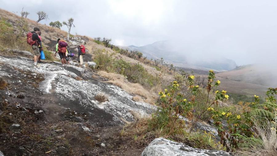 Walkers pick their way down a rocky slope as cloud closes in across the valley.